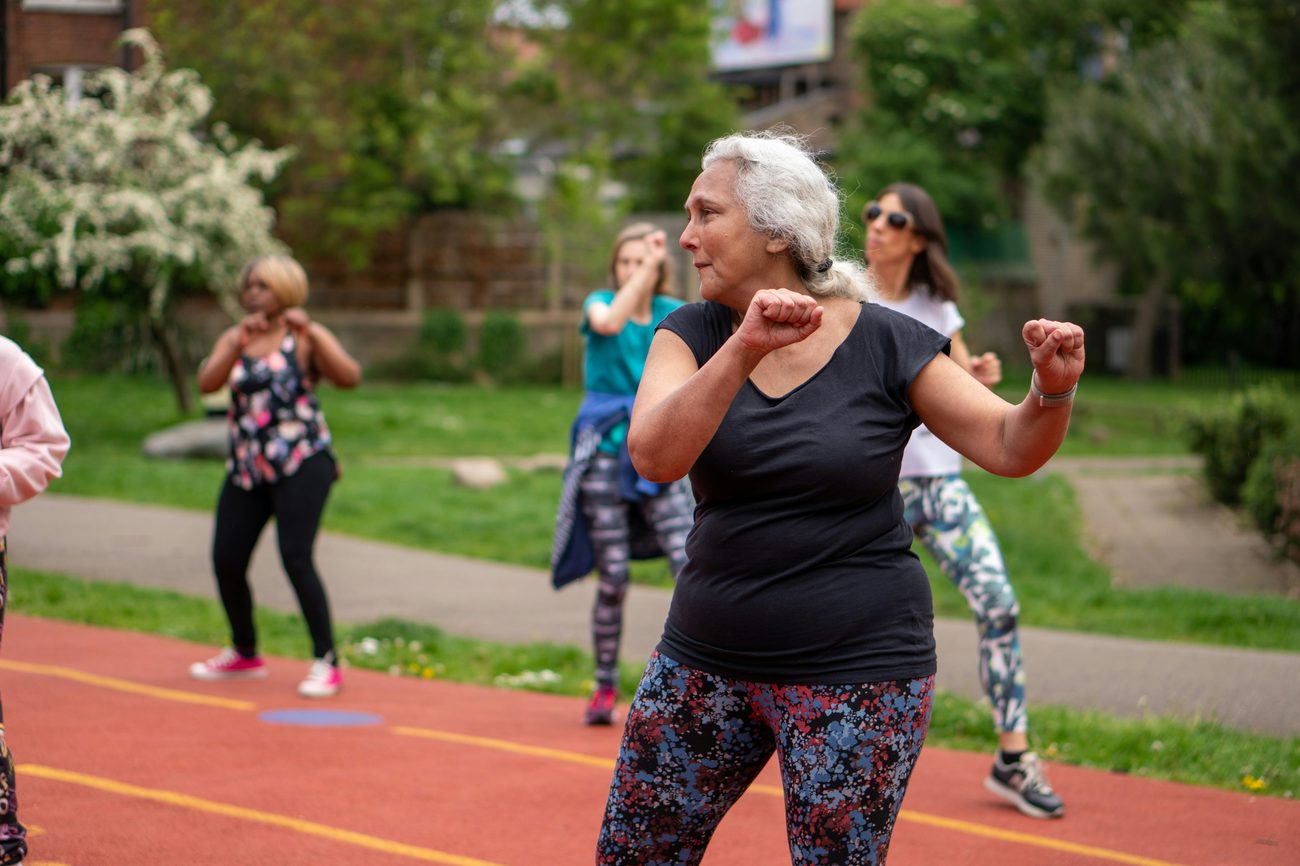 Woman in her 50s dancing energetically in an outdoor fitness class