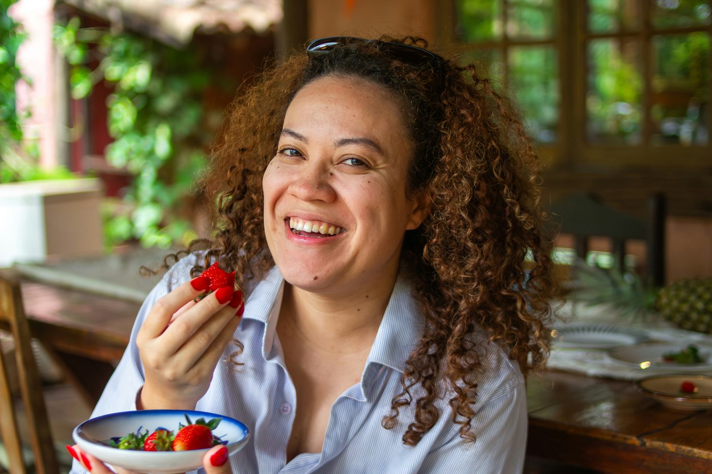 Woman in her 40s smiling and enjoying fresh fruit outdoors