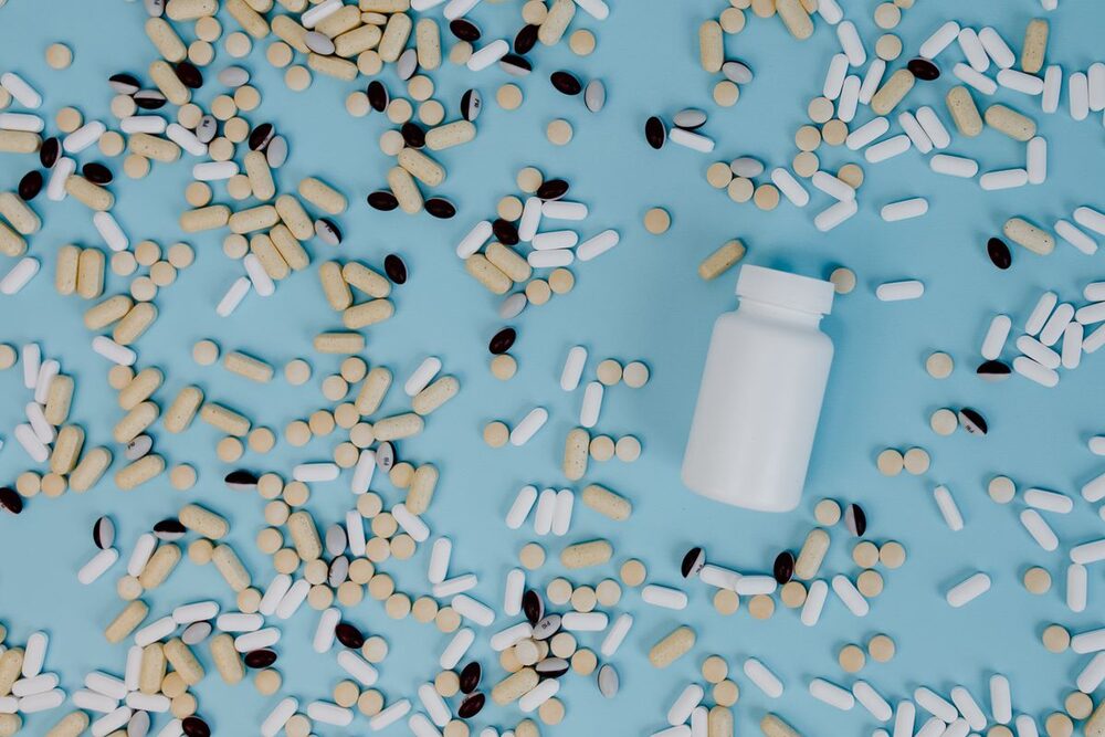 A white supplement bottle surrounded by tablets